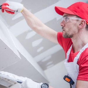 Skilled contractor smoothing drywall.